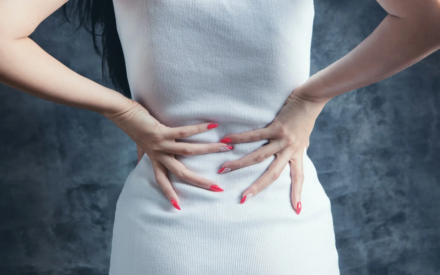 A person resting a hand against their lower back where the pain sits