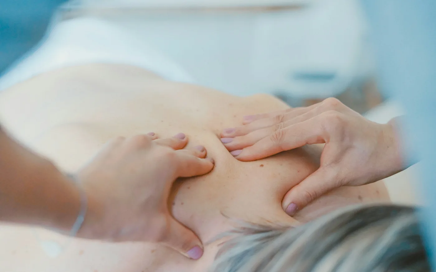 A therapist working across the neck and shoulders during a massage