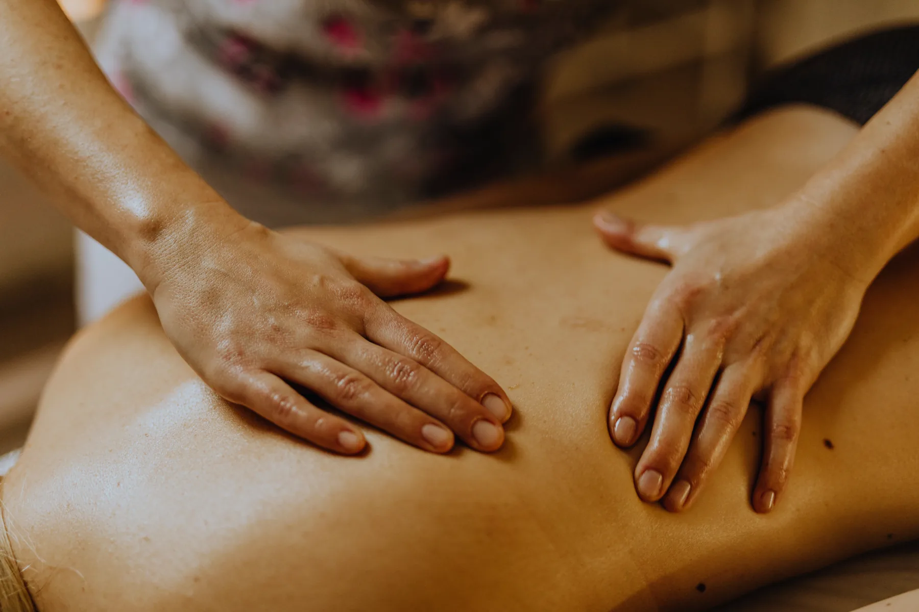 A massage therapist working with both hands across a client&rsquo;s back during a treatment.