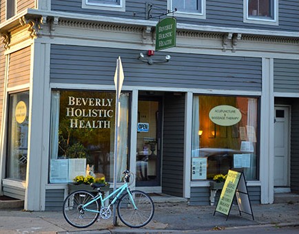 The Beverly Holistic Health practice at 146 Cabot Street, Beverly, Massachusetts: a grey clapboard storefront with gold lettering on the window and a hanging sign.