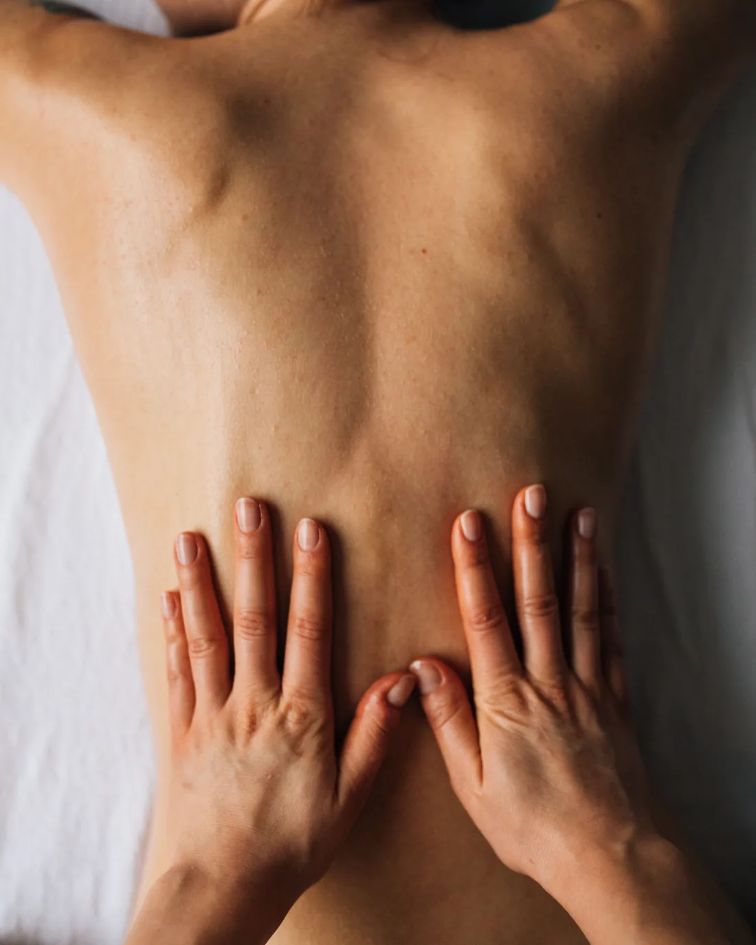 A massage therapist working with both hands along a person&rsquo;s back during a treatment.