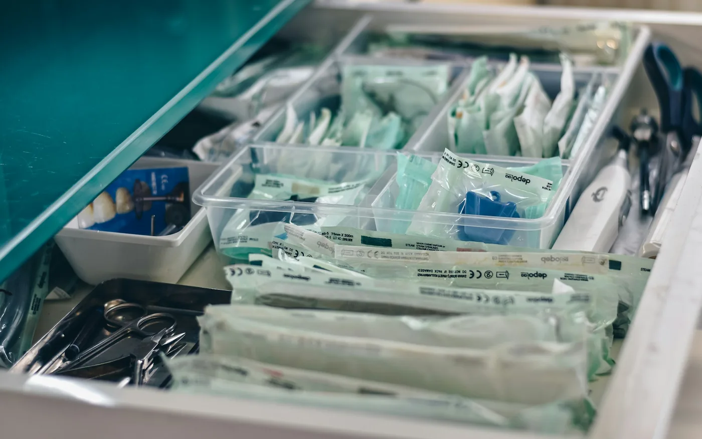 Single-use needles in sealed sterile packaging, opened in front of the patient